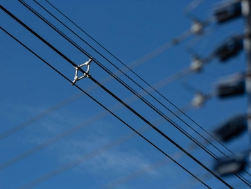 Snapshot of a electricity wire from a pylon against a blue sunny sky.