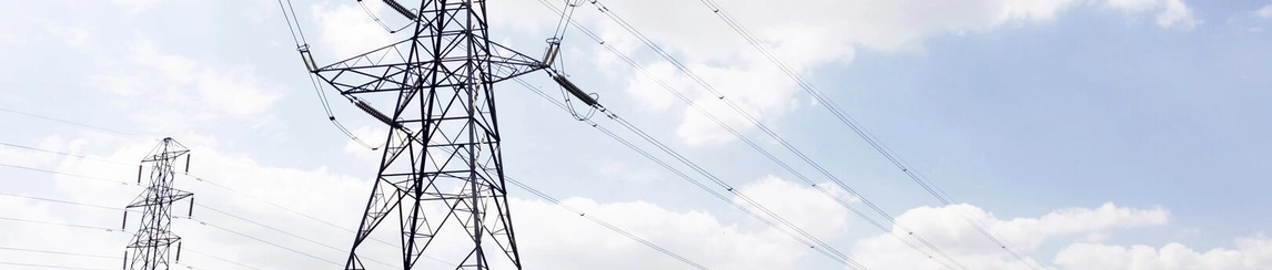 Multiple electricity pylons in a green field.