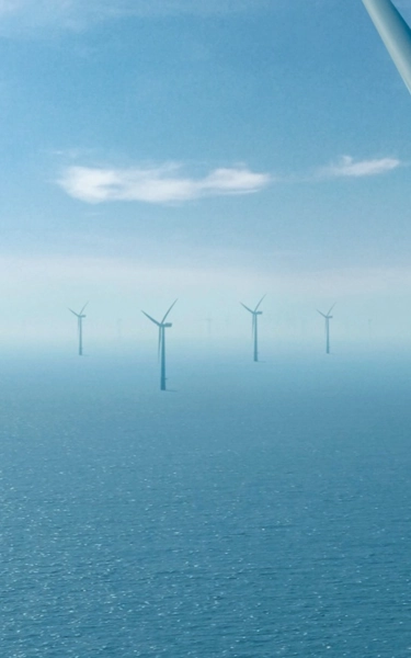 White large offshore wind turbines in the spinning in the ocean.