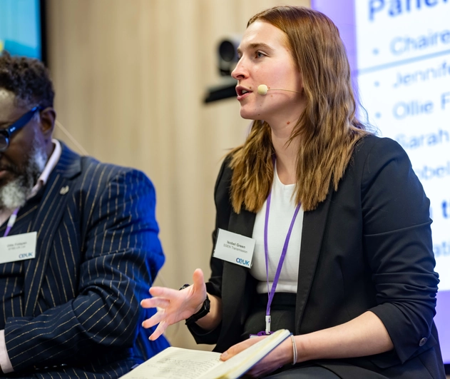 Female speaking at a conference with a microphone attached to their head.
